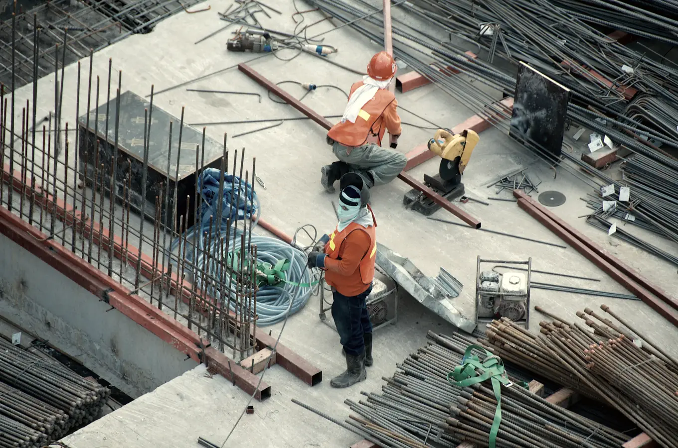 Steel reinforcement being tied and set out by hand across a poured slab.