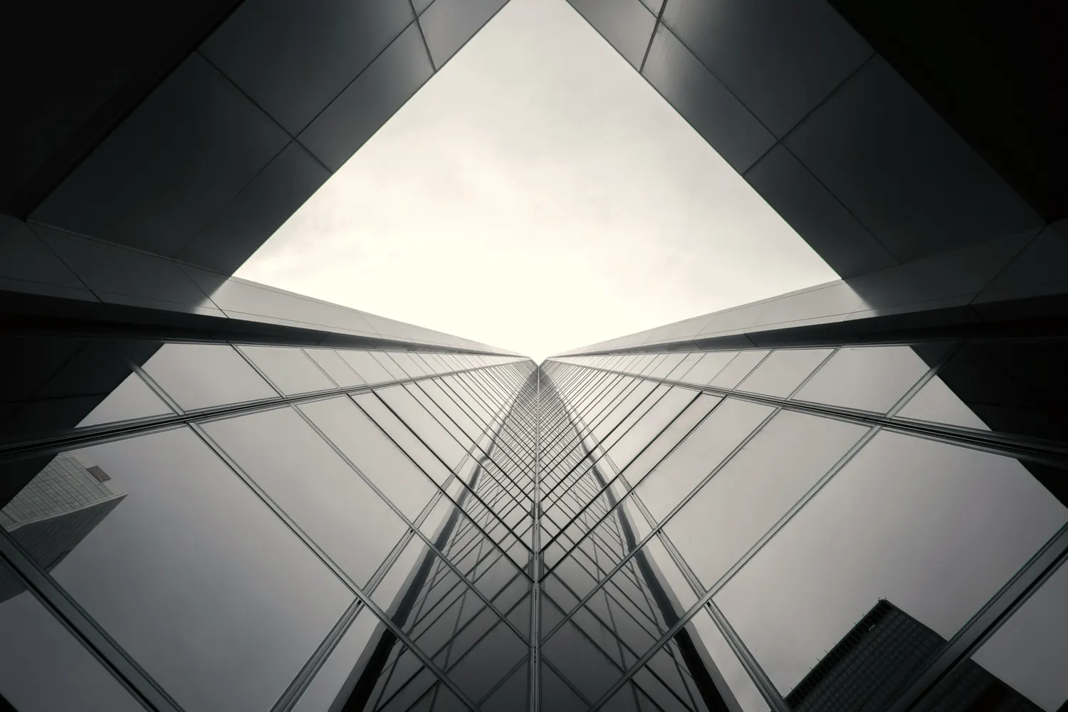 Looking up between two towers, their glass facades converging on a bright sky.